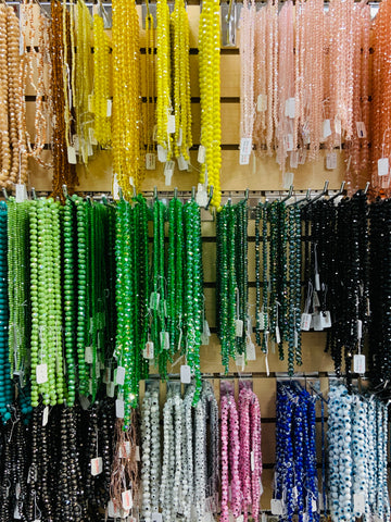 Faceted Rondelle Glass Beads in strands, shown on a wall