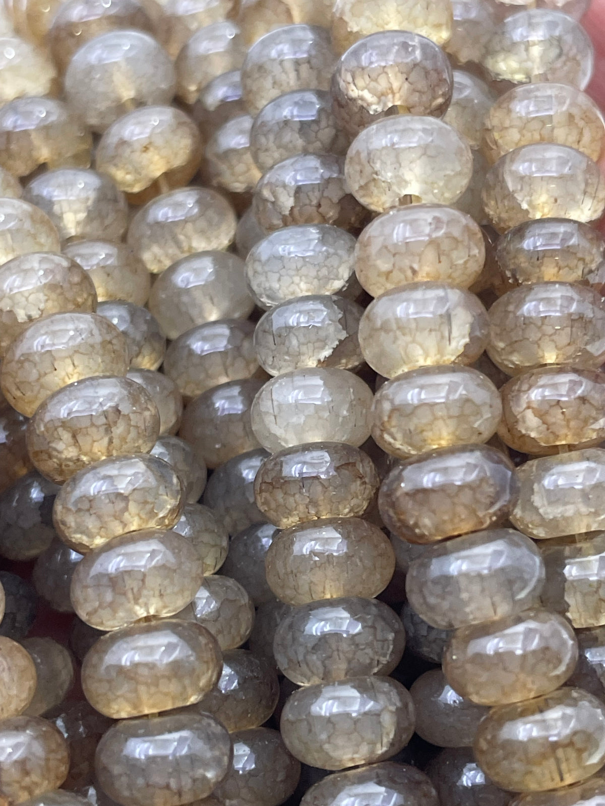 Close-up of a strand of smooth donut glass translucent beads in a smoky amber-brown color with natural crystalline texture.
