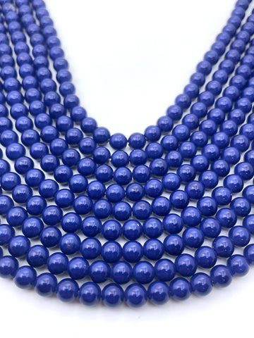 Multiple strands of polished royal blue beads arranged in curved rows on a plain white background.