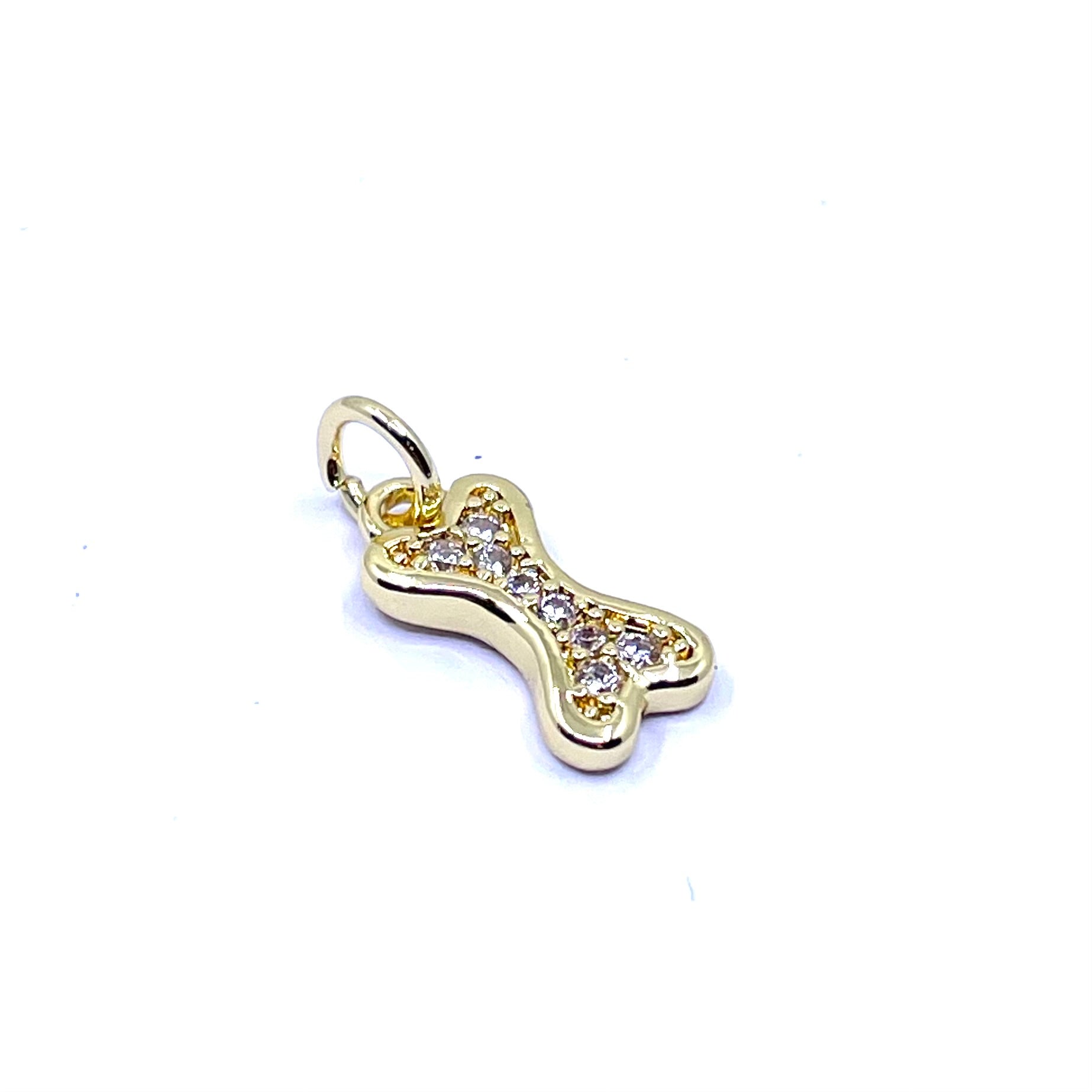 A gold bone-shaped charm pendant adorned with small clear crystals, shown on a plain white background.