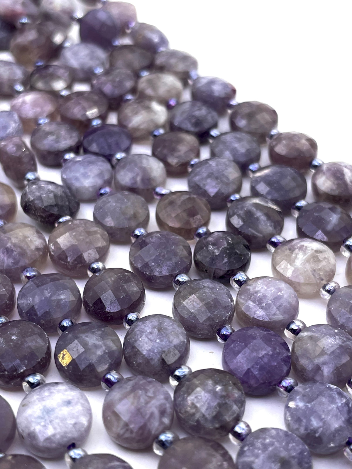 Faceted round lepidolite gemstone beads in shades of lavender, gray, and smoky purple, strung together on a white background.