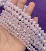 Pink glass beads shown on hand for size reference