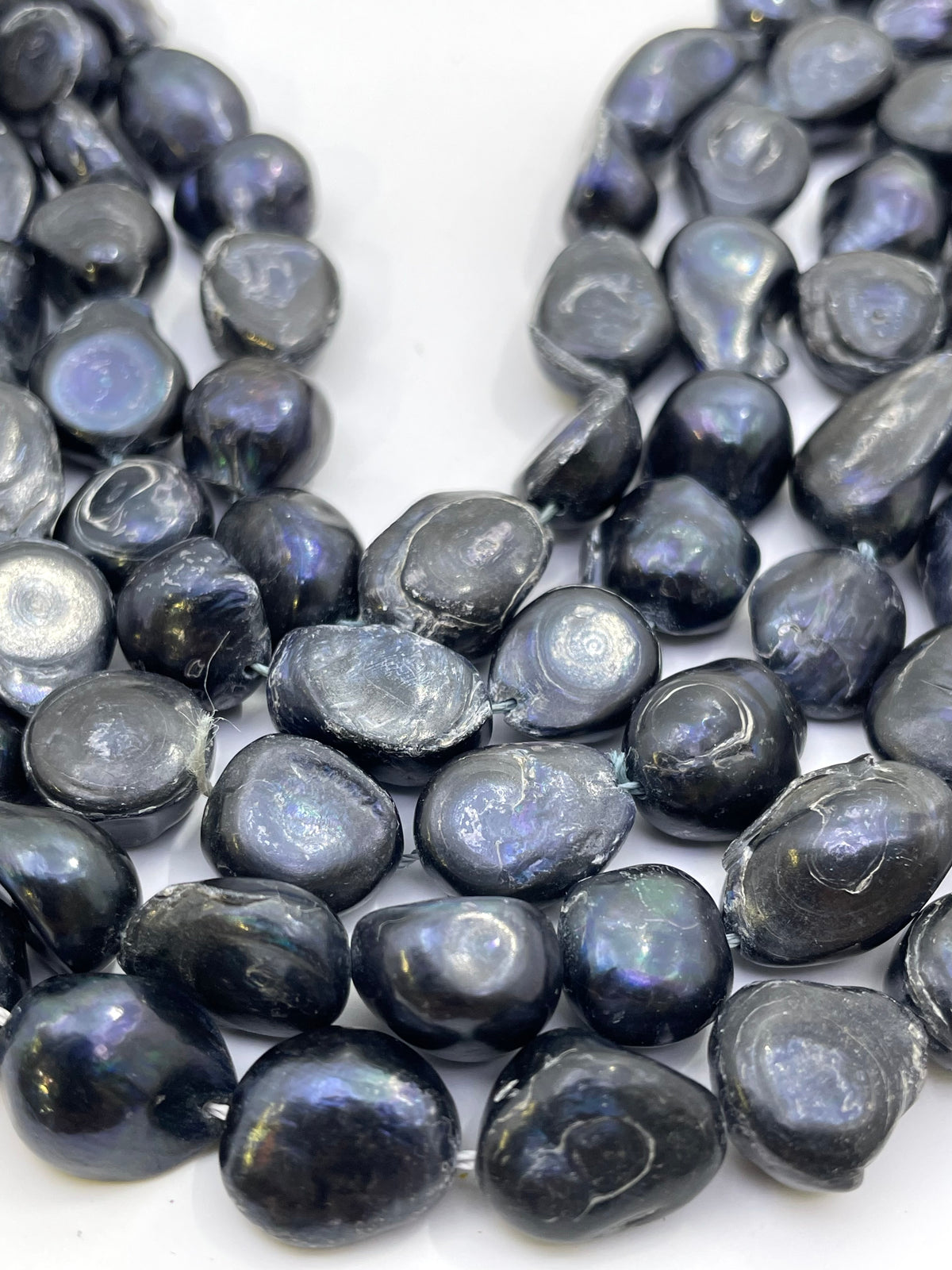 Close-up of dark iridescent baroque beads on a white background.