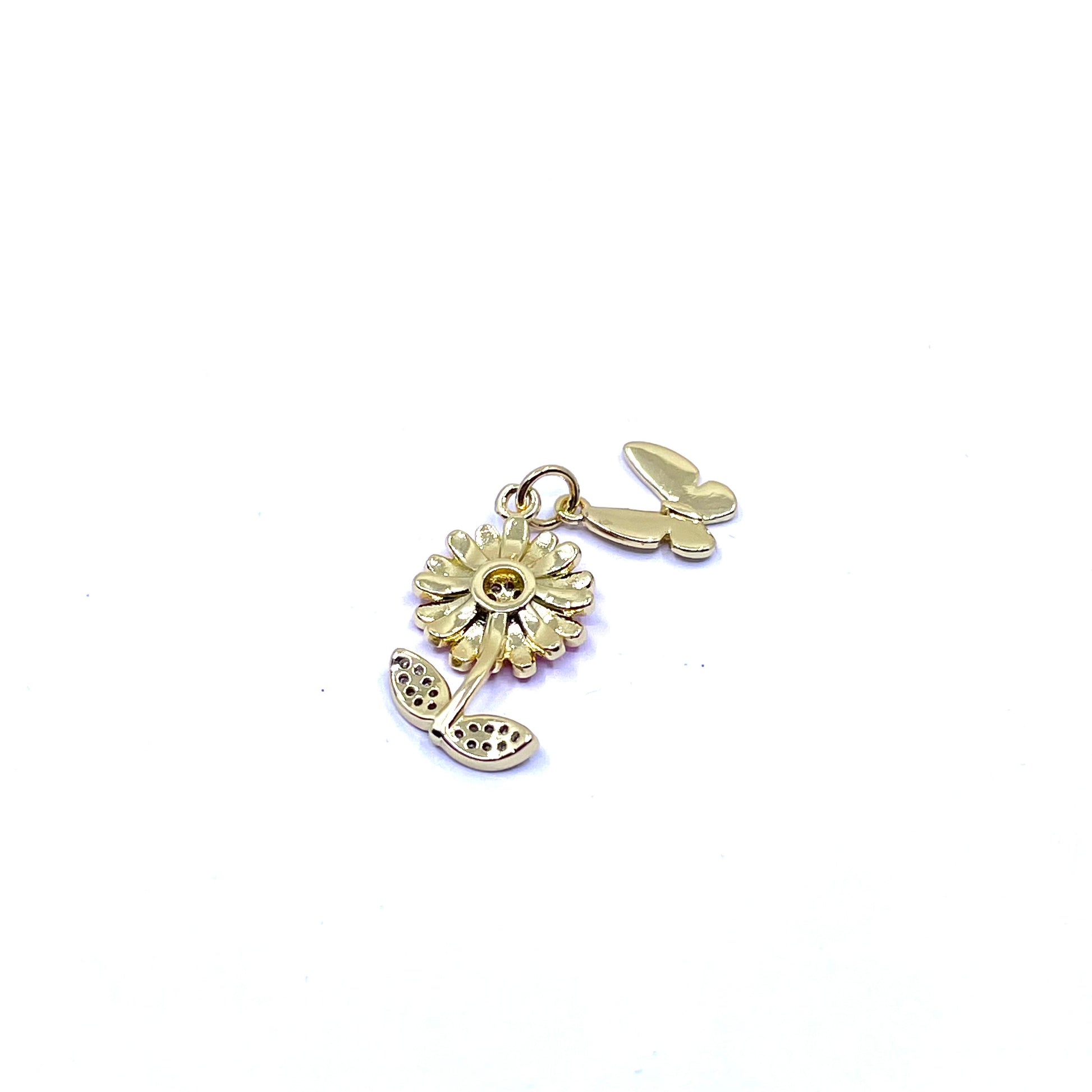 A small gold charm featuring a flower with a butterfly, photographed on a plain white background.