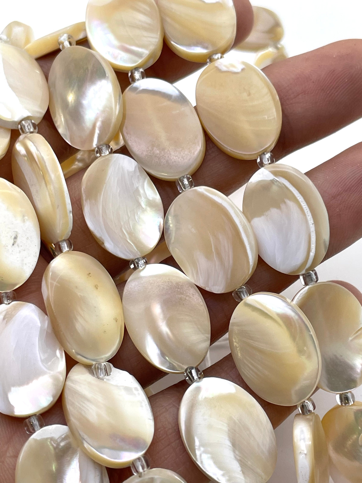 Oval mop caramel beads in a hand for size reference