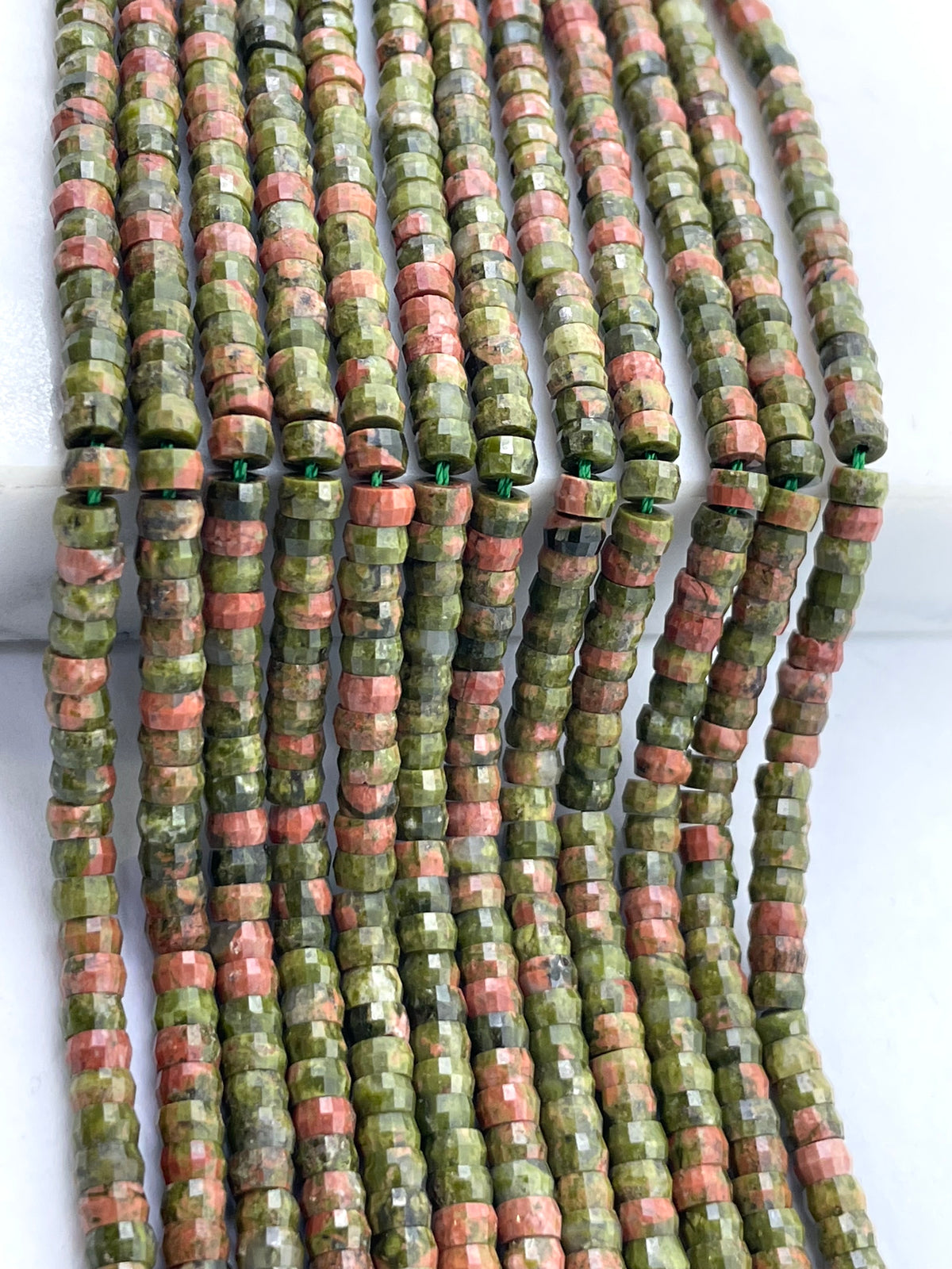 Faceted unakite beads strung on multiple strands, featuring a mix of olive green, terracotta pink, and brown colors.