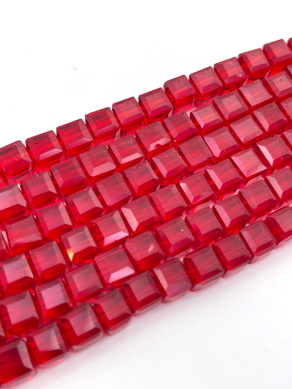 Faceted red glass beads arranged in diagonal rows on a plain white background.