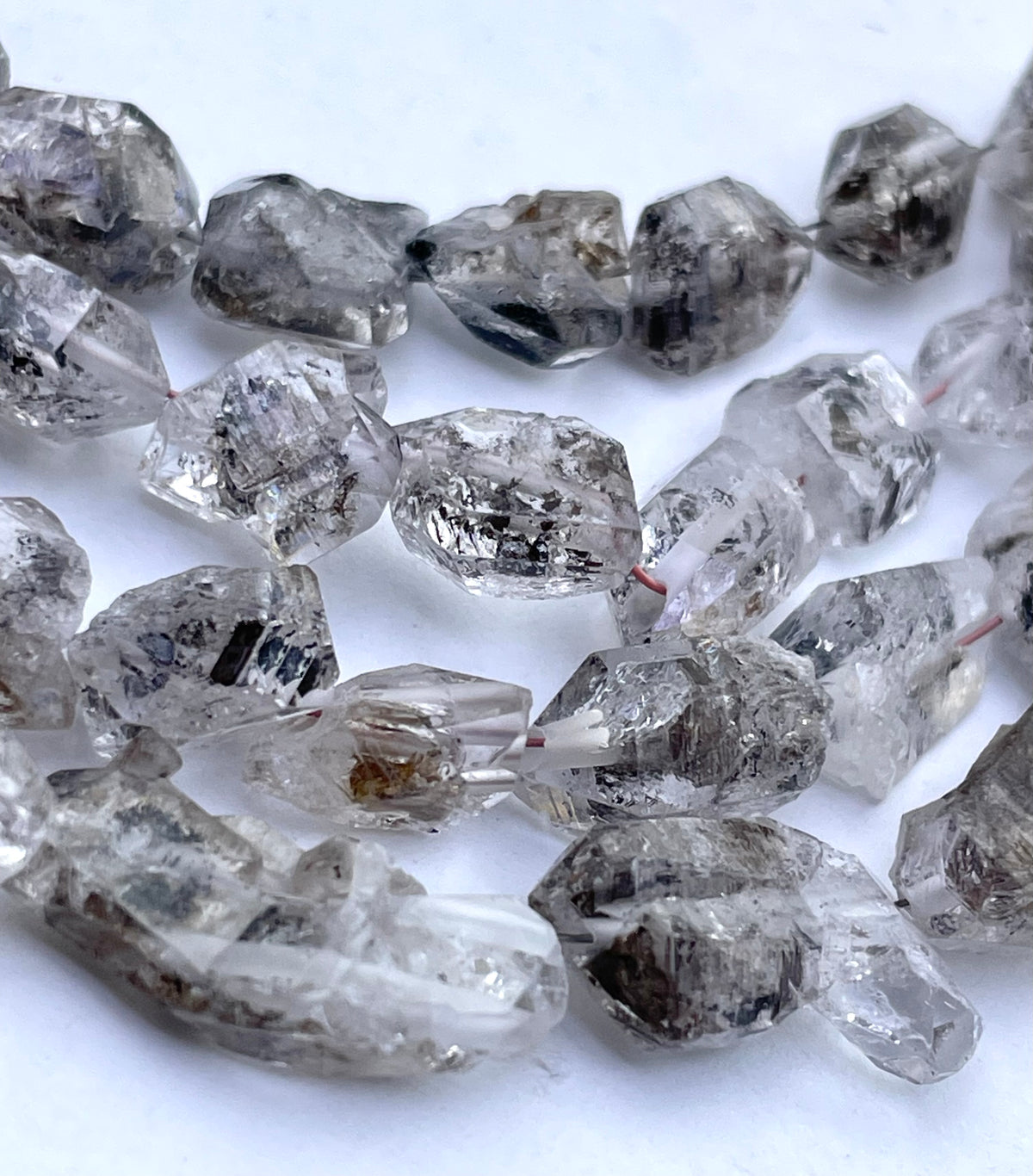 Herkimer diamond beads with natural inclusions, shown on a white background.