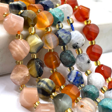 Close-up of multiple strands of faceted gemstone beads with gold spacer beads, featuring a variety of colors including orange, pink, blue, green, gray, and white.