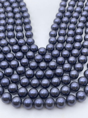 Multiple strands of glossy, dark blue-gray round pearls arranged on a plain white background.