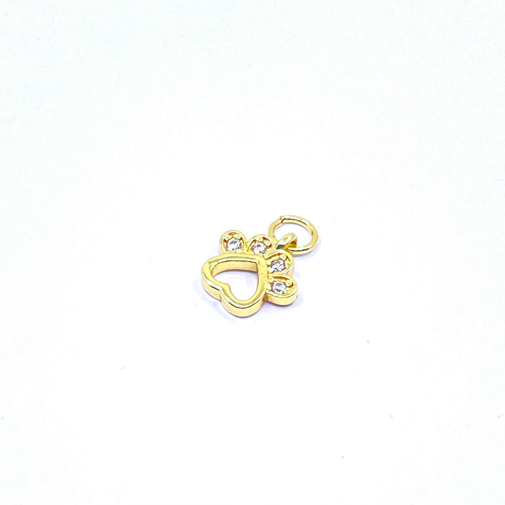 A small gold charm shaped like a heart with a paw print above it, featuring three clear rhinestones, on a plain white background.