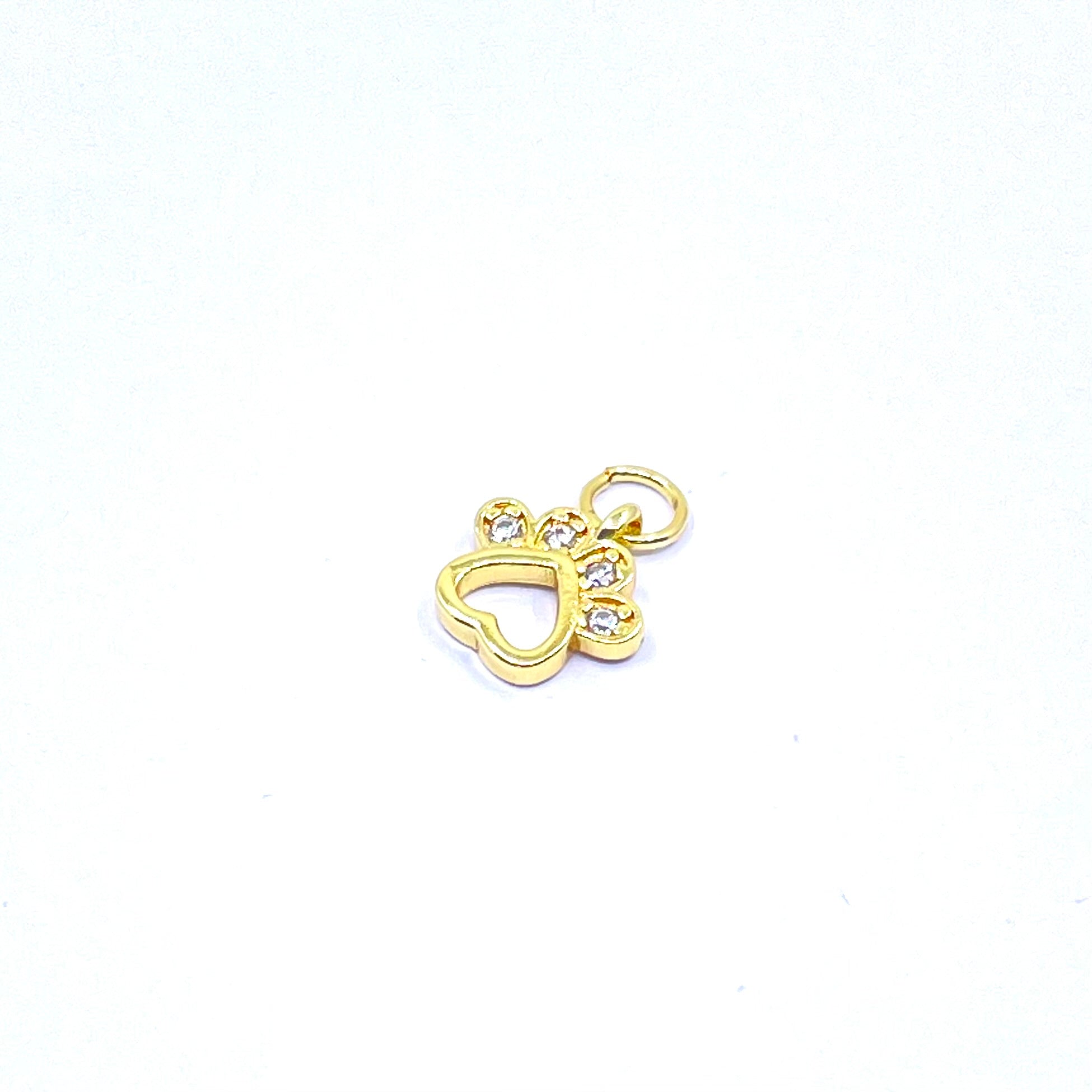 A small gold charm shaped like a heart with a paw print above it, featuring three clear rhinestones, on a plain white background.