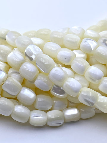 A close-up of glossy, rounded rectangular beads with a pearlescent white and soft cream color, arranged in overlapping coils on a plain white background.