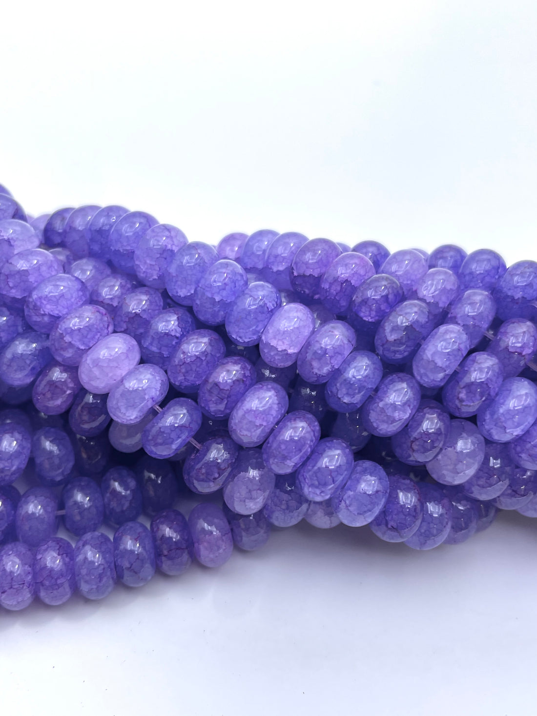 Smooth donut glass purple beads against a white background