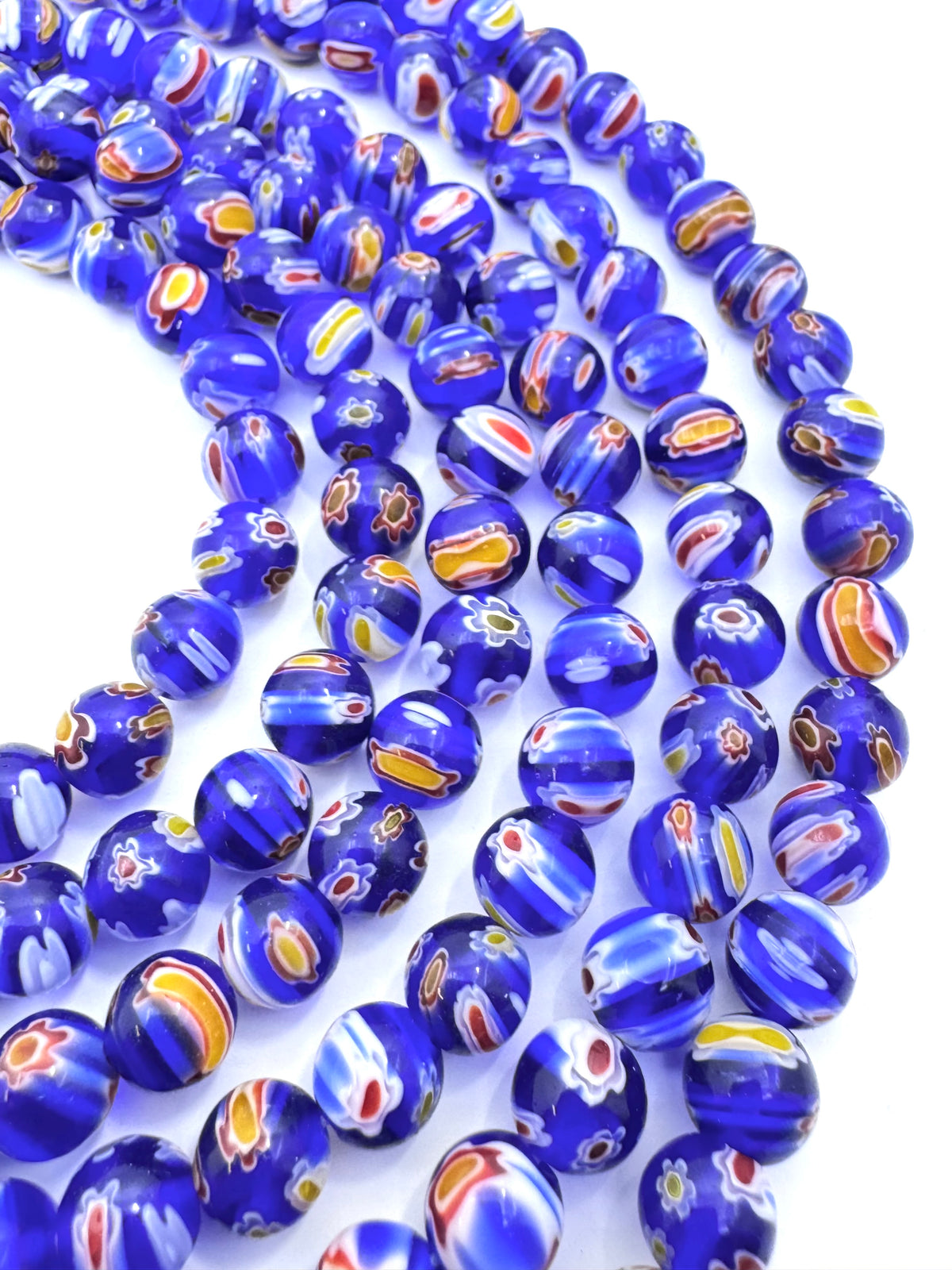 Multiple strands of round glass beads in a cobalt blue color, featuring multicolored swirls of white, yellow, orange, and red on a white background.