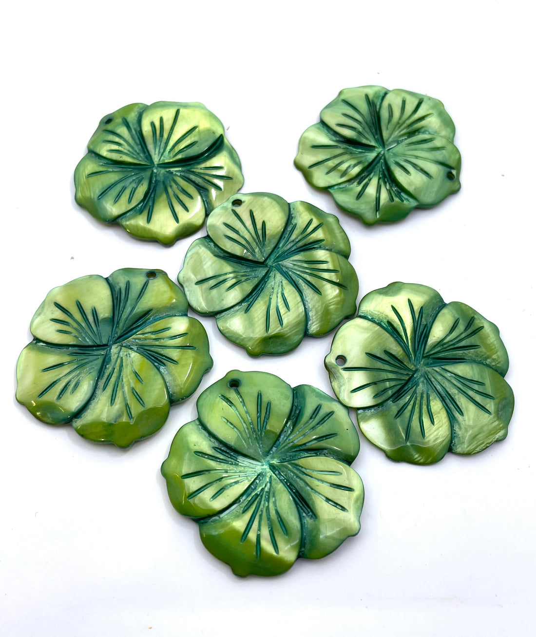 Five green mother of pearl flower pendants with embossed leaf-like details, arranged on a plain white background.