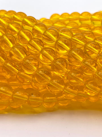 A close-up of translucent amber yellow glass beads strung together on a white background.