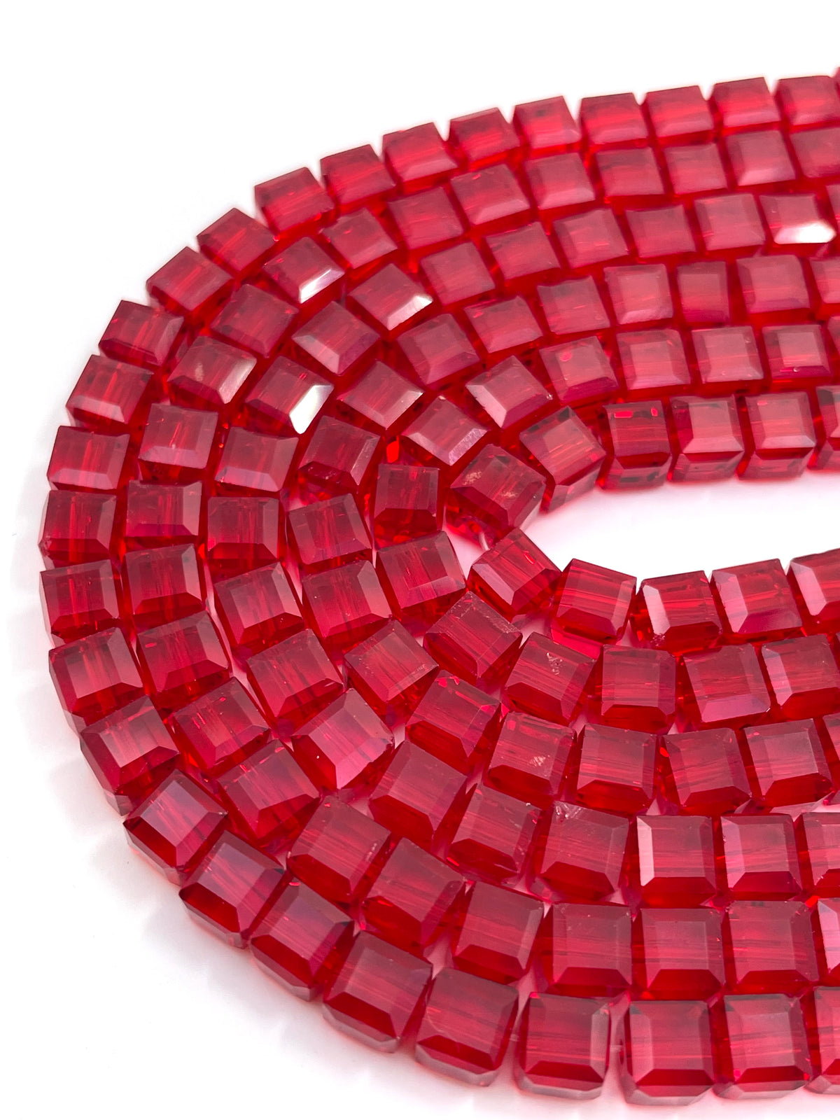 A close-up of a coiled strand of faceted red beads on a plain white background.