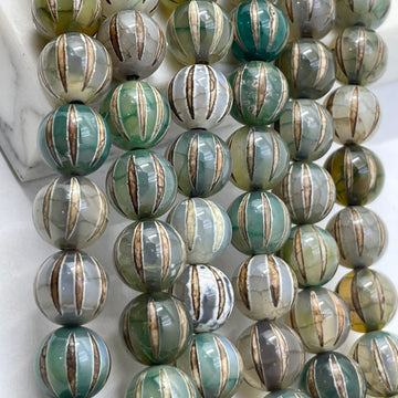 A close-up of round tibetan agate dzi beads strung in rows, featuring a marbled pattern of green, gray, white, and metallic gold vertical stripes.