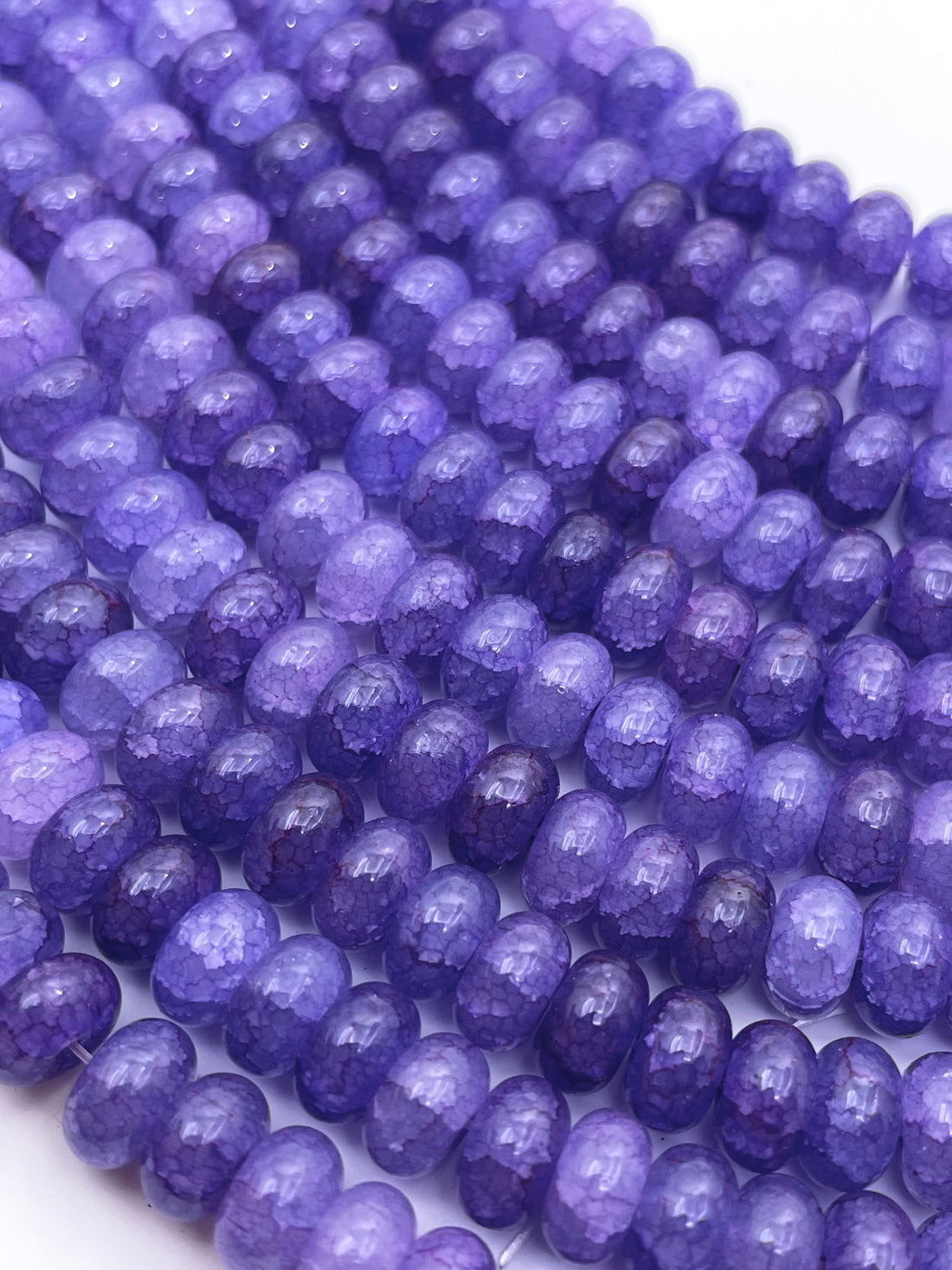 Smooth donut glass purple beads against a white background