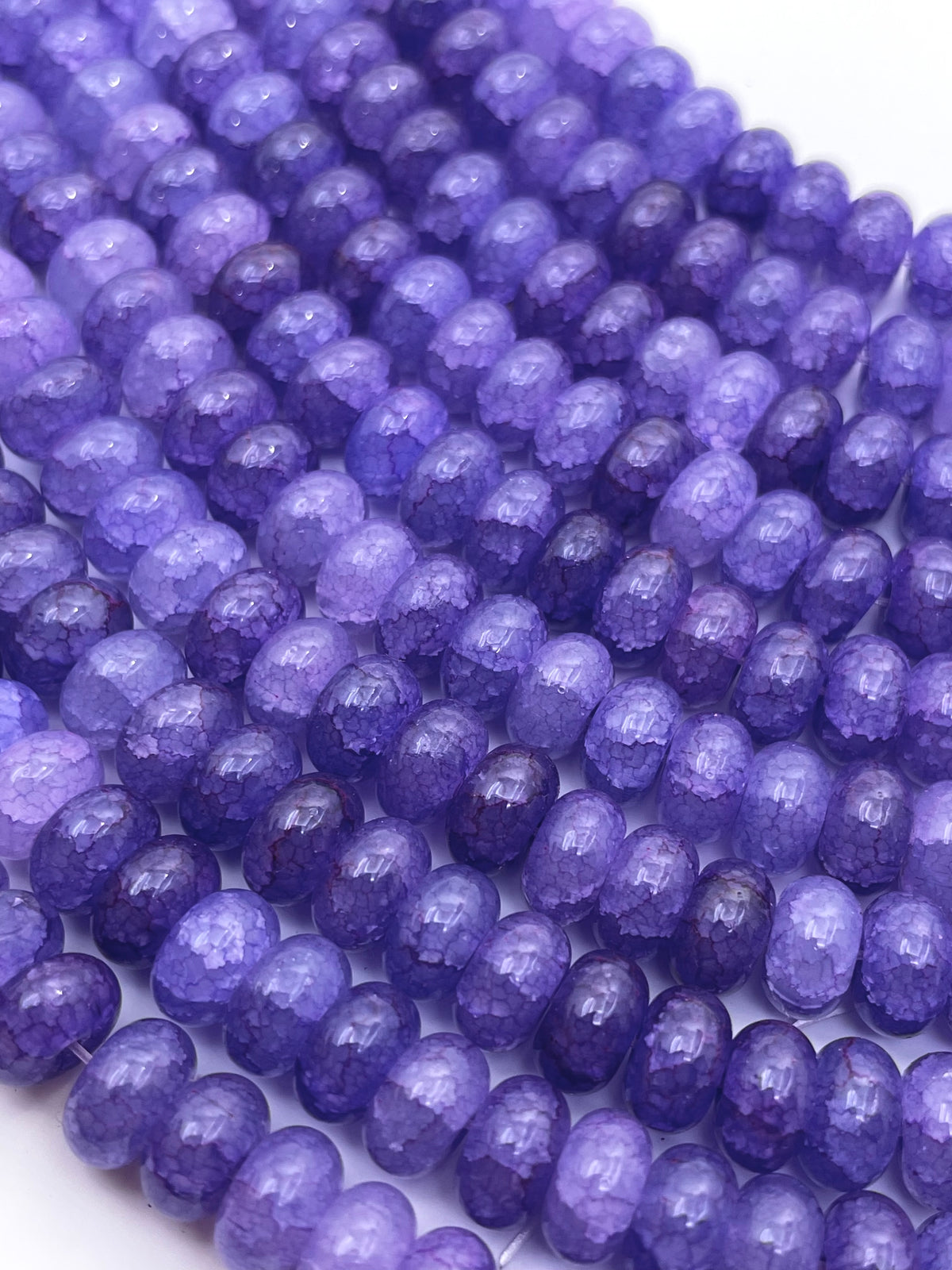 Smooth donut glass purple beads against a white background