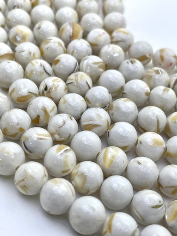 Ivory round mop beads with natural tan and brown inclusions, arranged in diagonal rows on a white background.