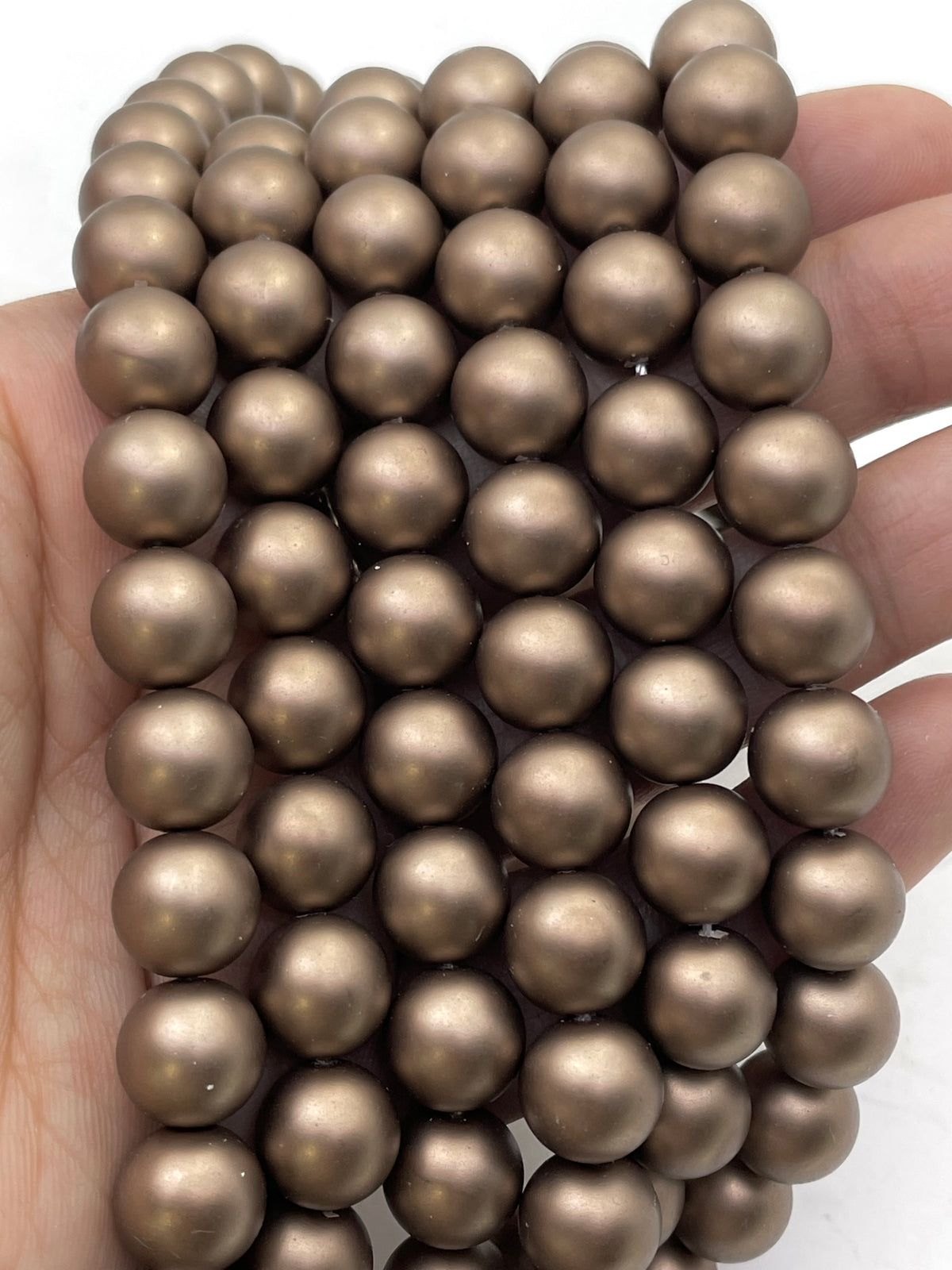 Chocolate brown shell pearls shown on hand for size reference