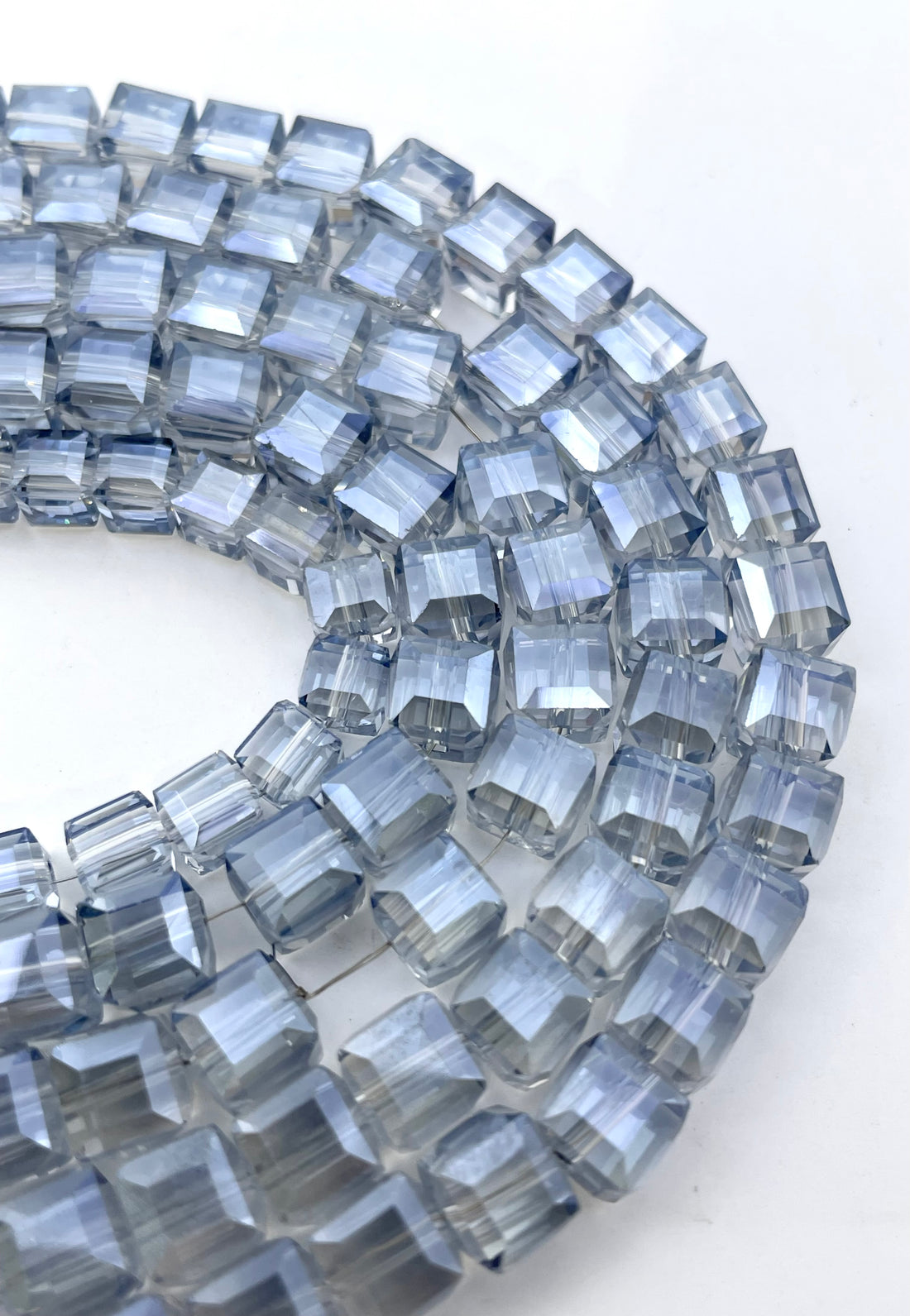 Light montana blue glass beads arranged in curved pattern.