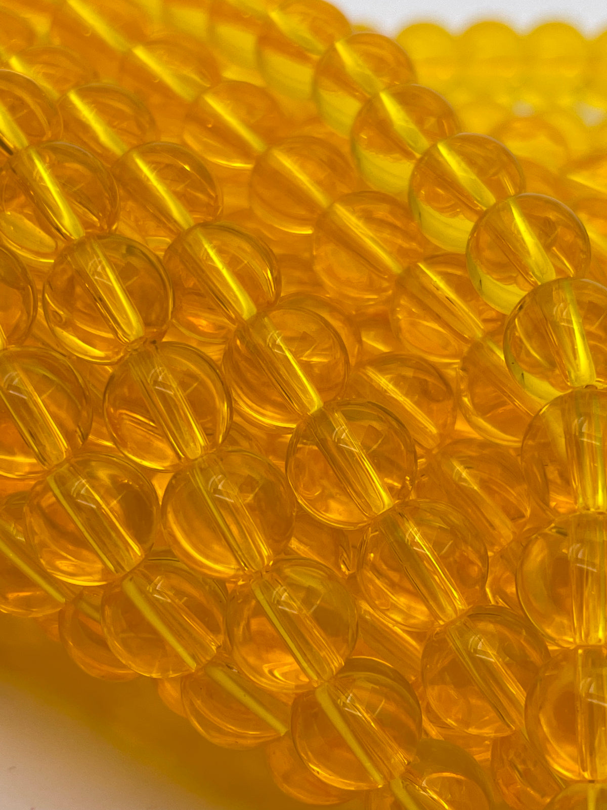 Close-up of translucent amber-yellow round beads strung on a cord, filling the frame with a soft-focus background.