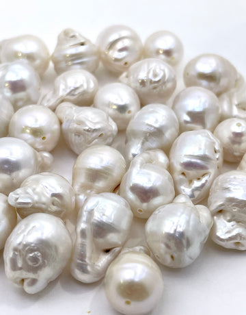 A pile of irregular baroque freshwater pearls in a glossy white lustrous finish, photographed on a clean white background.