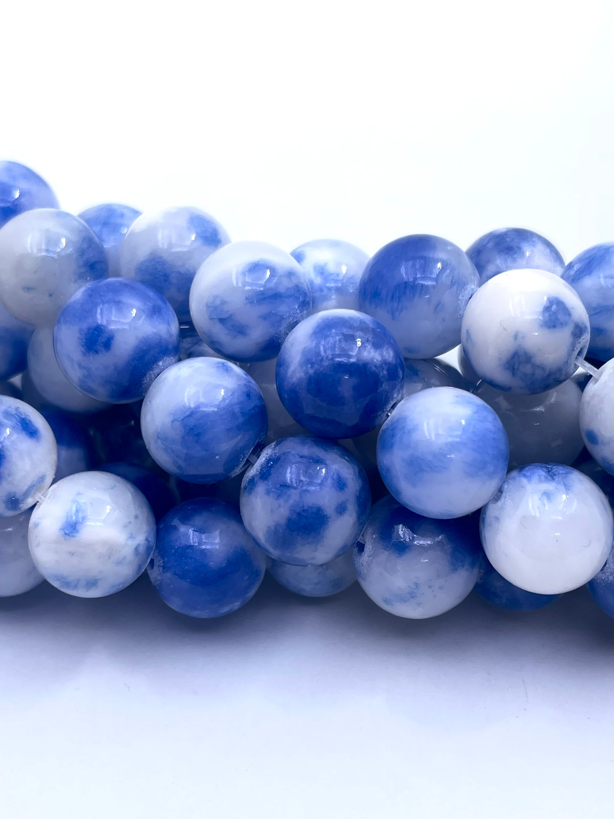 Blue and white marbled round persian jade beads arranged in a row on a white background.