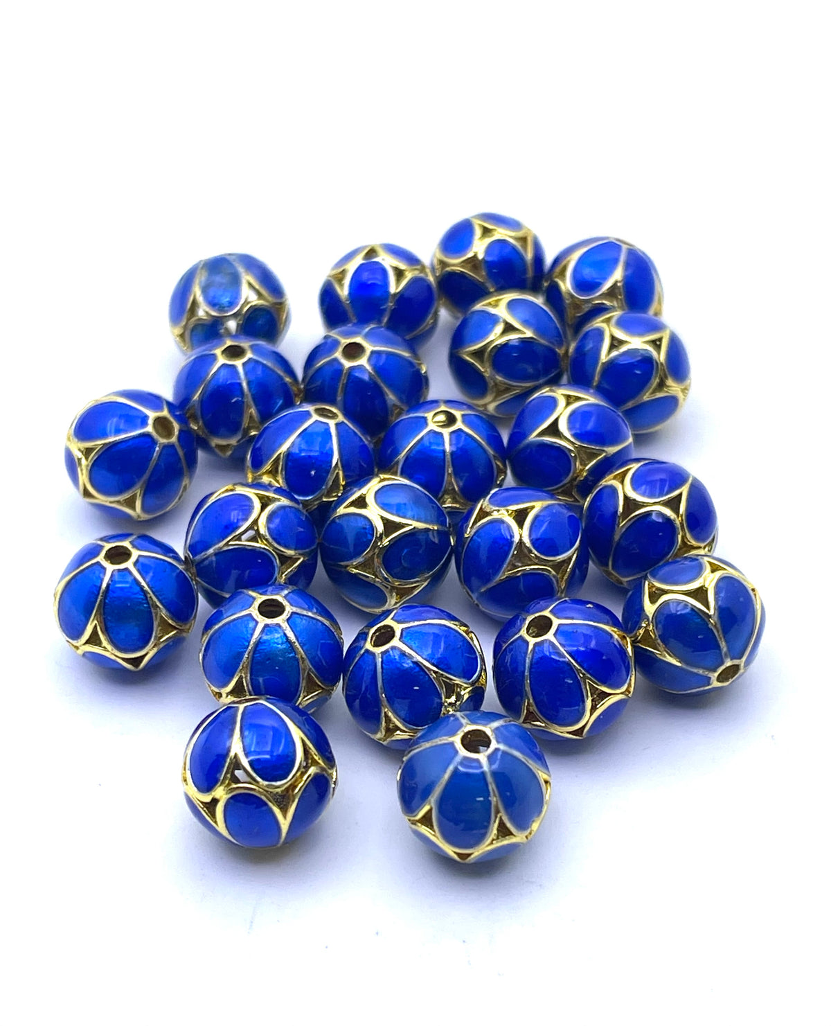 A pile of round blue glass beads with gold metal trim and cutout details, arranged on a plain white background.
