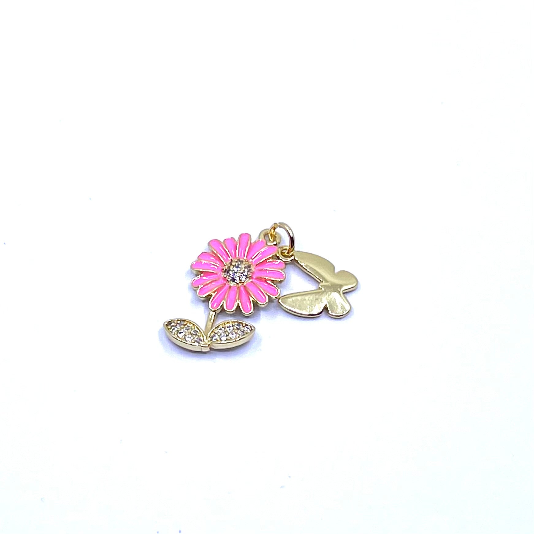 A gold-tone metal charm featuring a pink daisy flower with a clear rhinestone center and two small butterfly charms, shown on a plain white background.