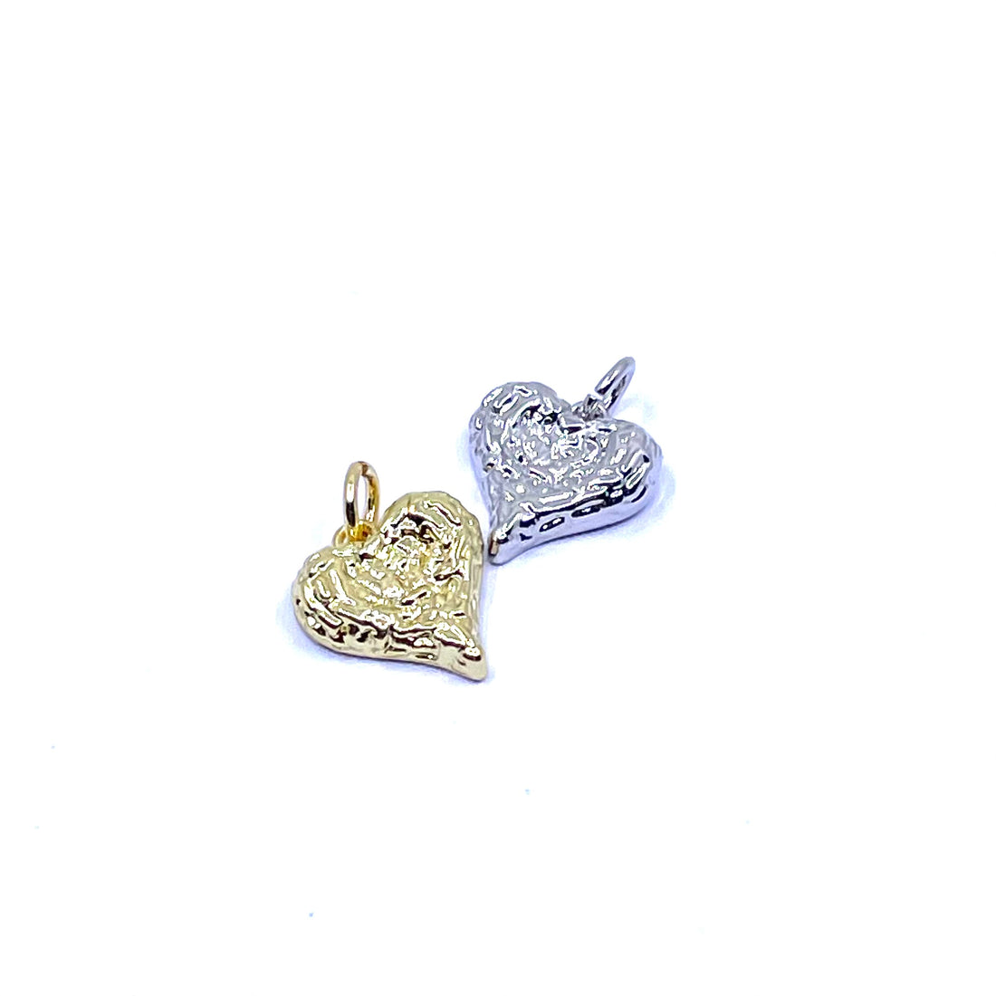Two textured heart-shaped charms, one in yellow gold and one in silver, shown on a plain white background.