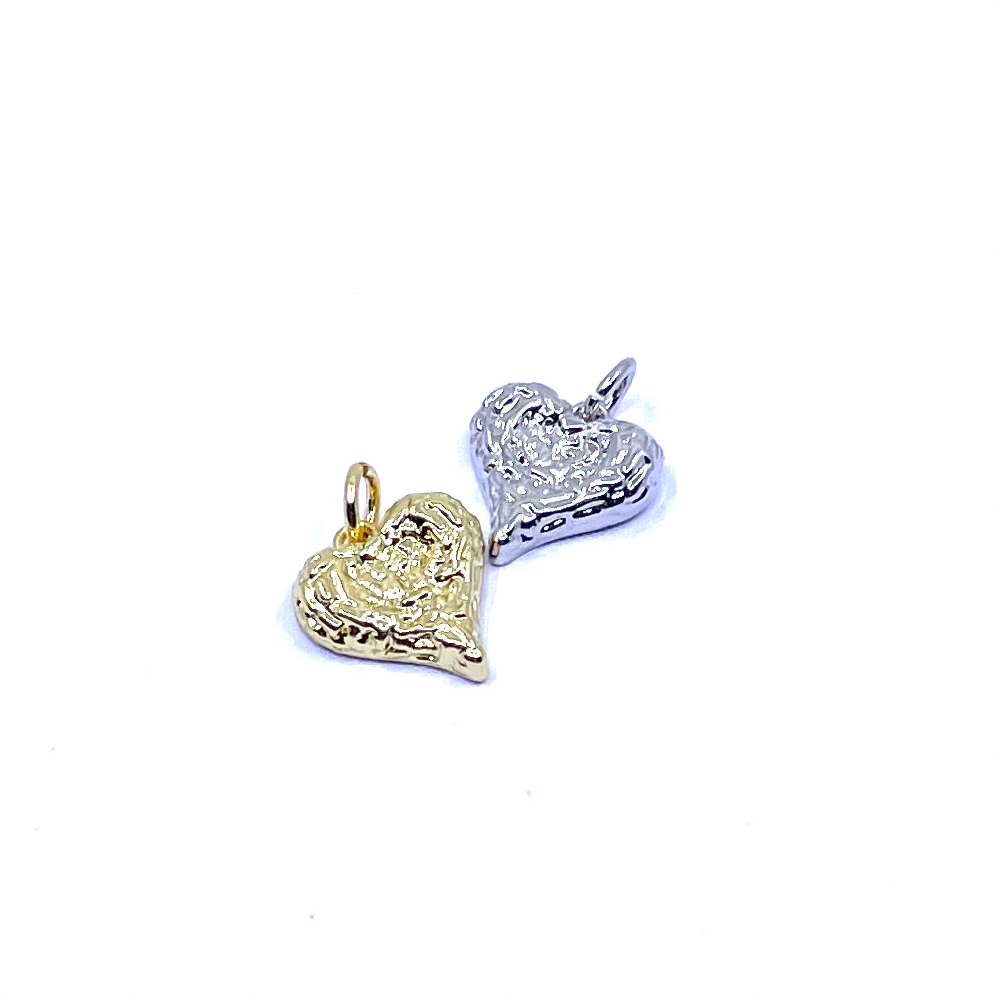 Two textured heart-shaped charms, one in yellow gold and one in silver, shown on a plain white background.