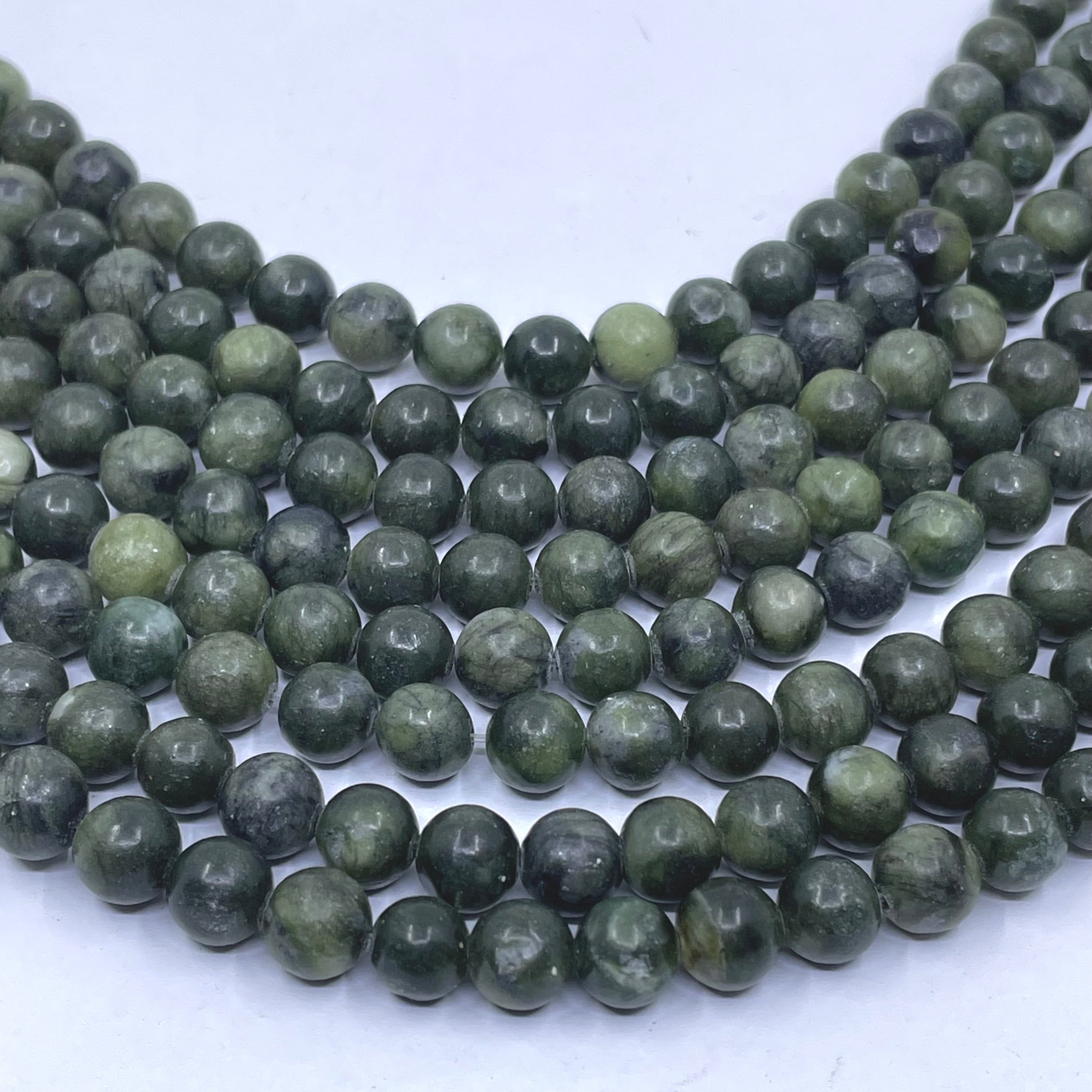 Multiple strands of round green jade stone beads arranged in curved rows on a plain white background.