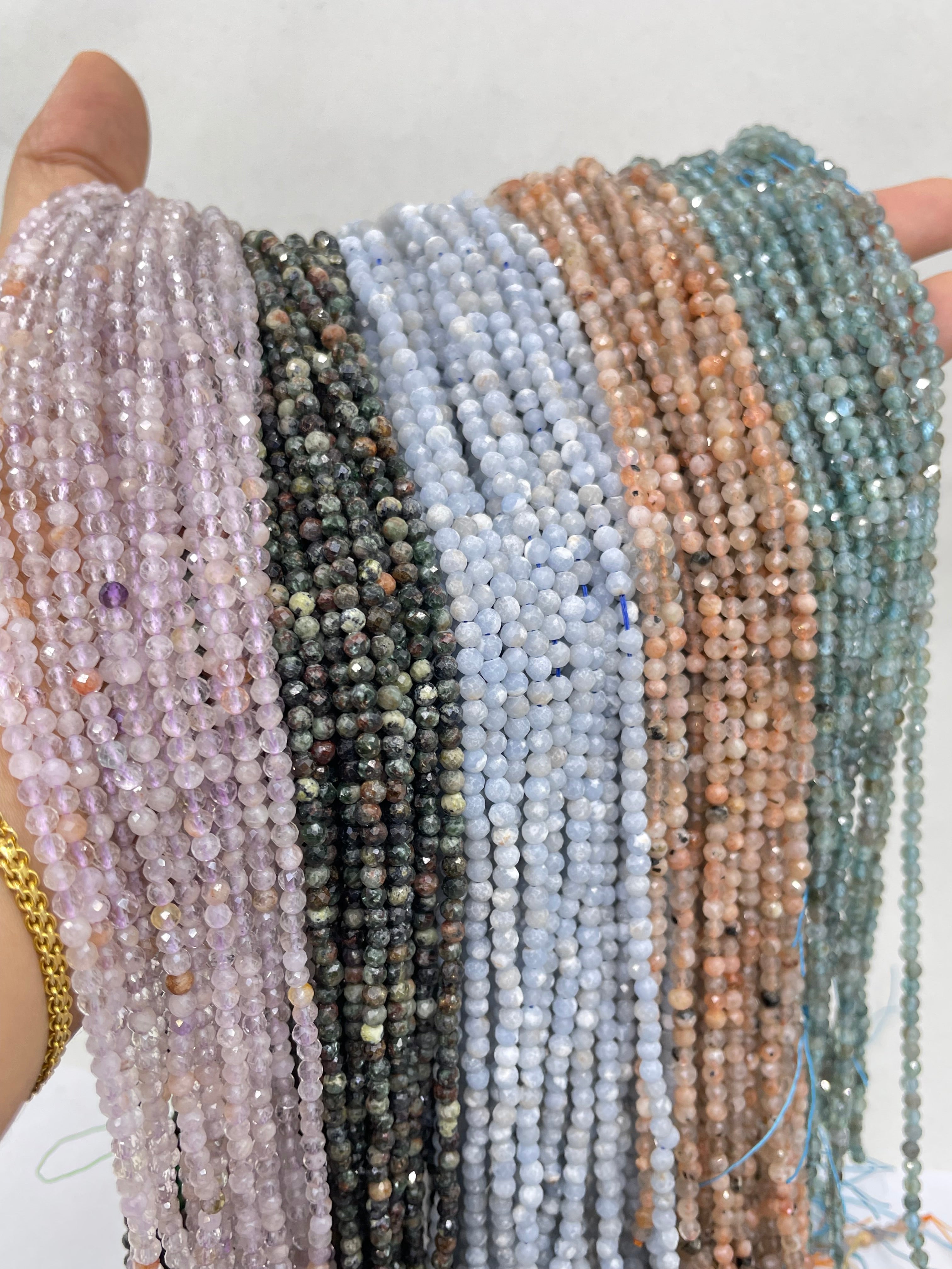 3mm round faceted light amethyst, serpentine, angelite, sunstone and light apatite displayed from left to right on hand to show size reference.
