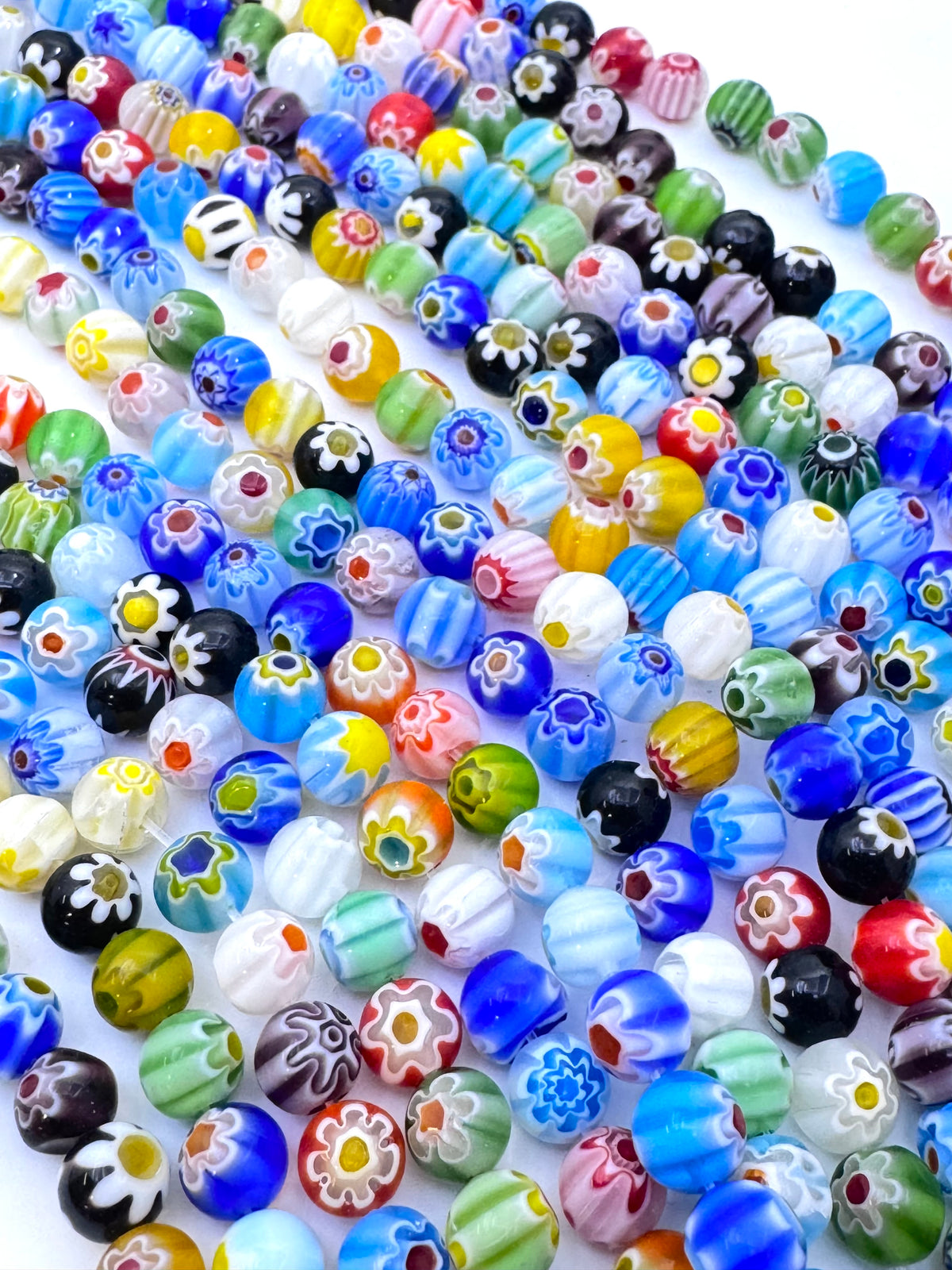 A dense collection of colorful glass bead strands featuring various patterns including floral, striped, and swirl designs in blue, red, green, yellow, white, and black.