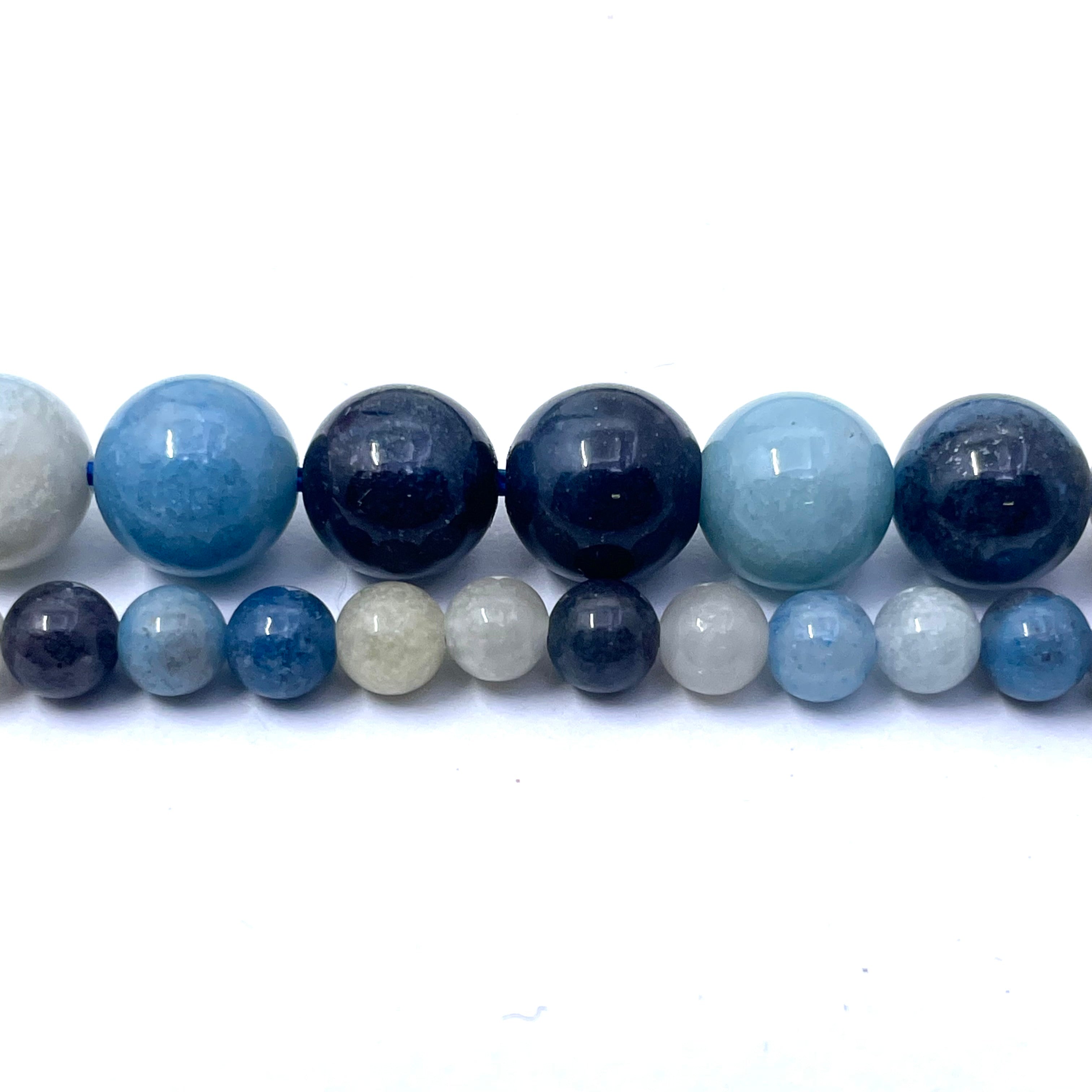 A strand of polished round gemstone beads in various sizes, featuring shades of light blue, dark navy, and white, arranged in two rows on a plain white background.