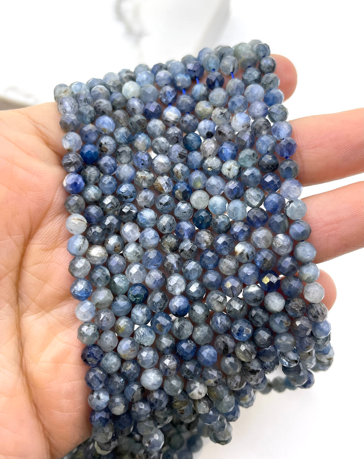 Faceted round kyanite beads on a hand
