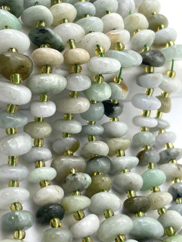 Multiple strands of polished burma jade stone beads in soft green, gray, white, and beige tones, separated by small metallic gold spacer beads, arranged closely together on a white background.