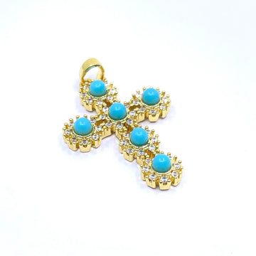 A gold cross pendant featuring SIX round turquoise-blue cabochon stones, each surrounded by a halo of small clear crystals, set against a plain white background.