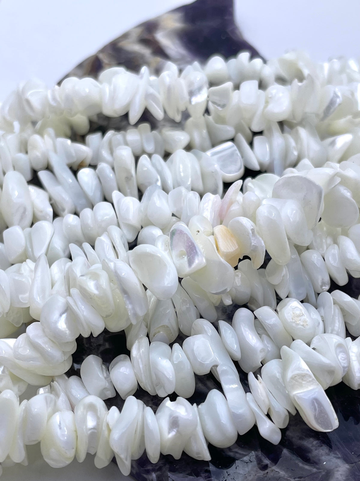 White pearl chip beads arranged on a dark surface, showing a glossy, lustrous finish.