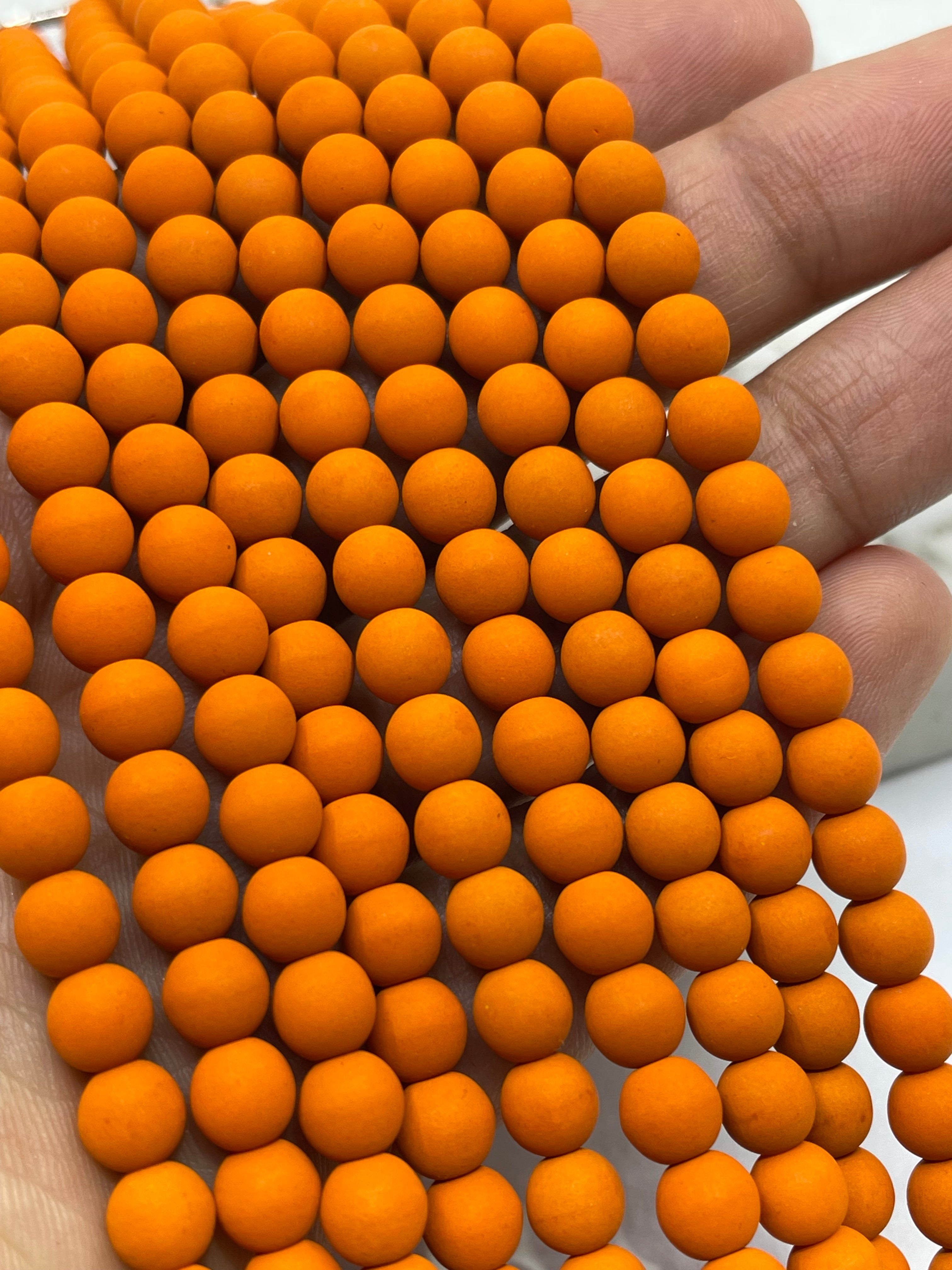 A close-up of orange velvet beads held across a person's fingers.