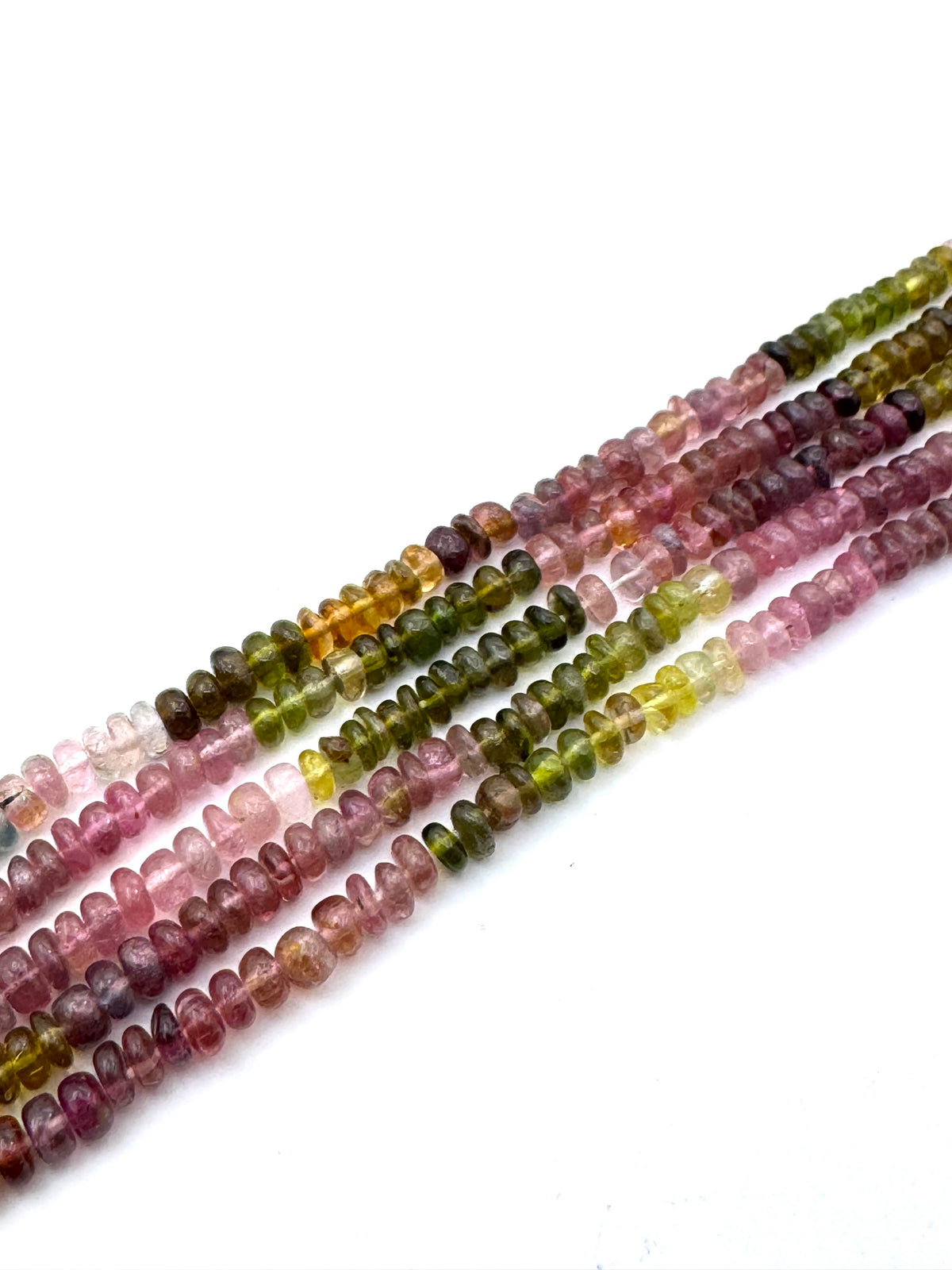 Five strands of small disc shape mix tourmaline beads arranged diagonally on a white background. The beads show a natural color gradient transitioning from pink and purple, through olive green, to yellow-green.