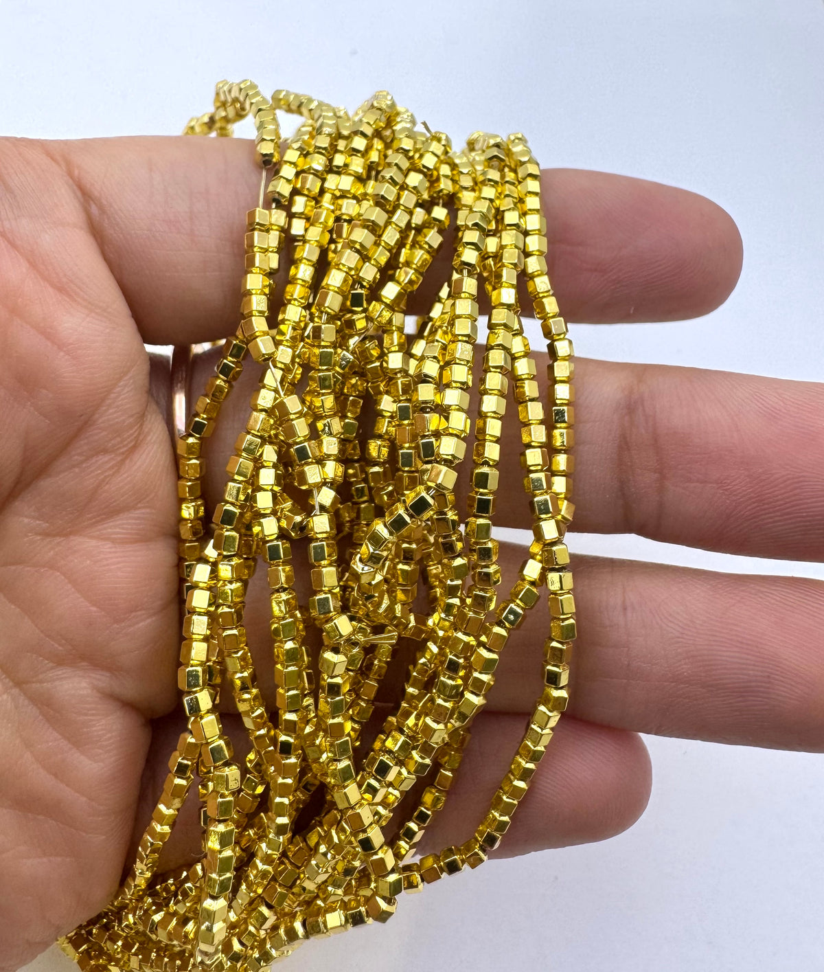 A hand holding a bundle of gold hematite beads