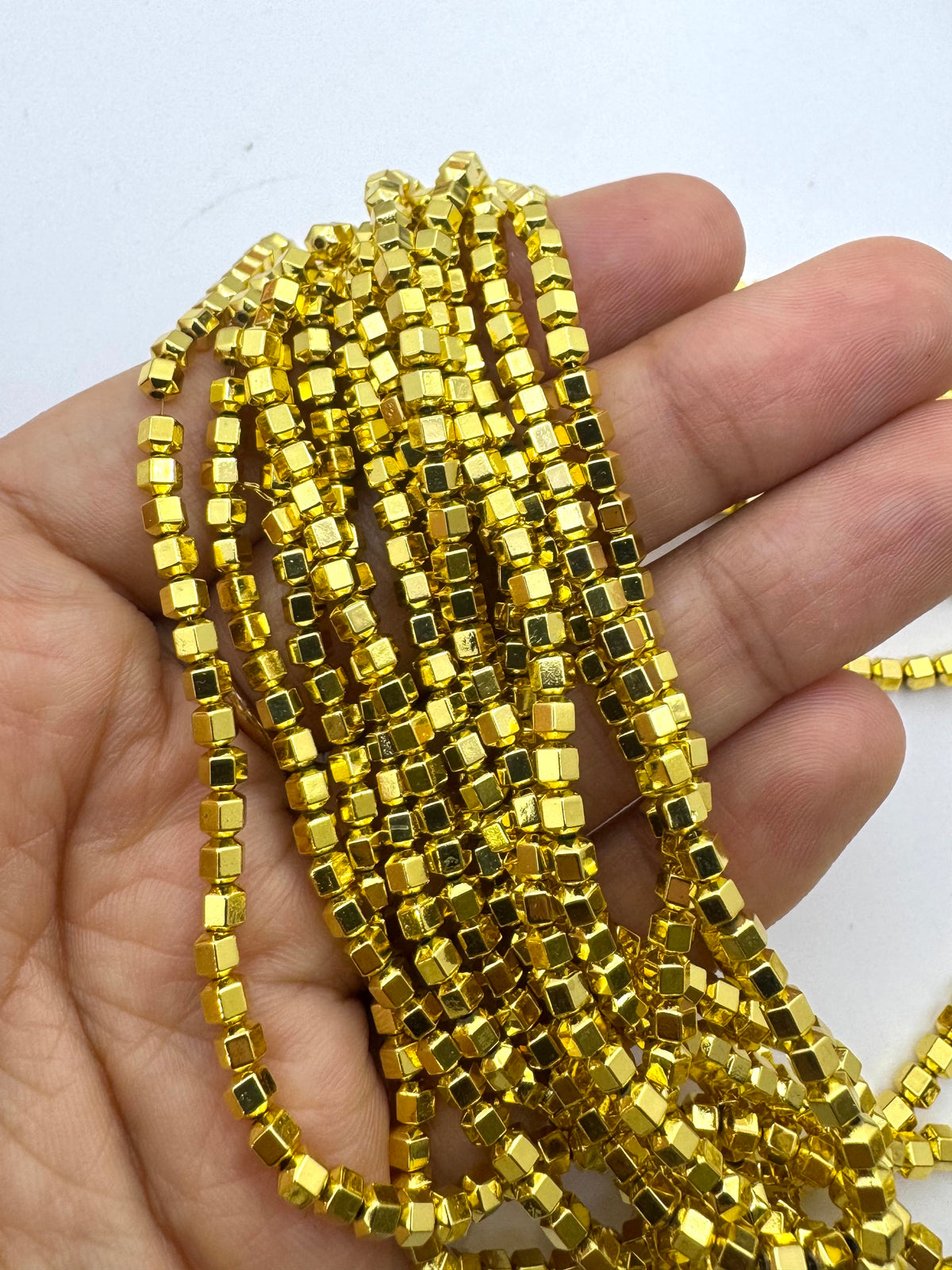 A hand holding a bundle of gold hematite beads