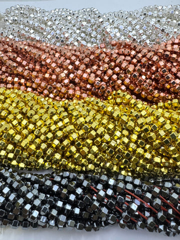 Multiple strands of metallic hematite beads arranged in horizontal rows, showing silver, rose gold, yellow gold, and gunmetal gray colors.