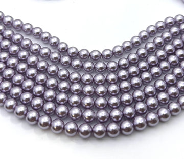 Multiple strands of small, glossy, dark purple-gray pearls arranged in a curved row on a plain white background.