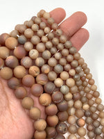 Natural Metallic Orange Druzy Agate beads shown on hand for size reference.